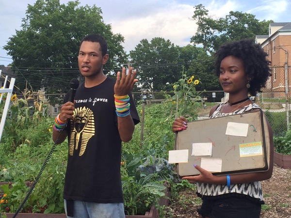 Trajan reports on his experience, while Aziza holds his visual aid, at the FRESH Urban Farm