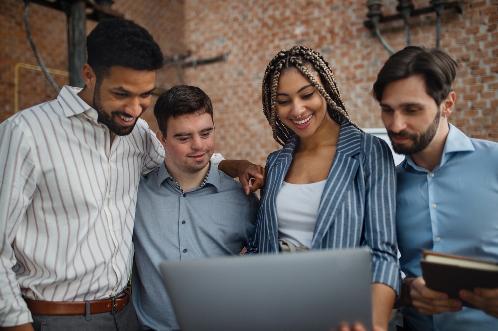 4 people looking at a tablet who may or may not have a disability